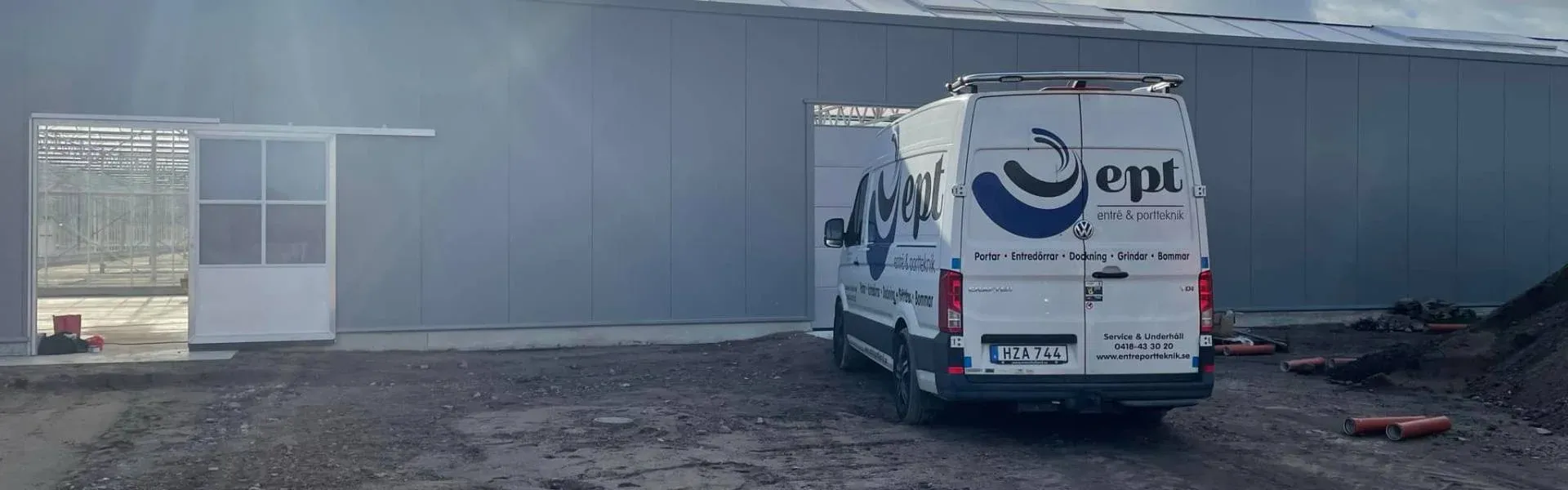 Servicebil från Entré och Portteknik vid en nymonterad skjutdörr på en byggarbetsplats